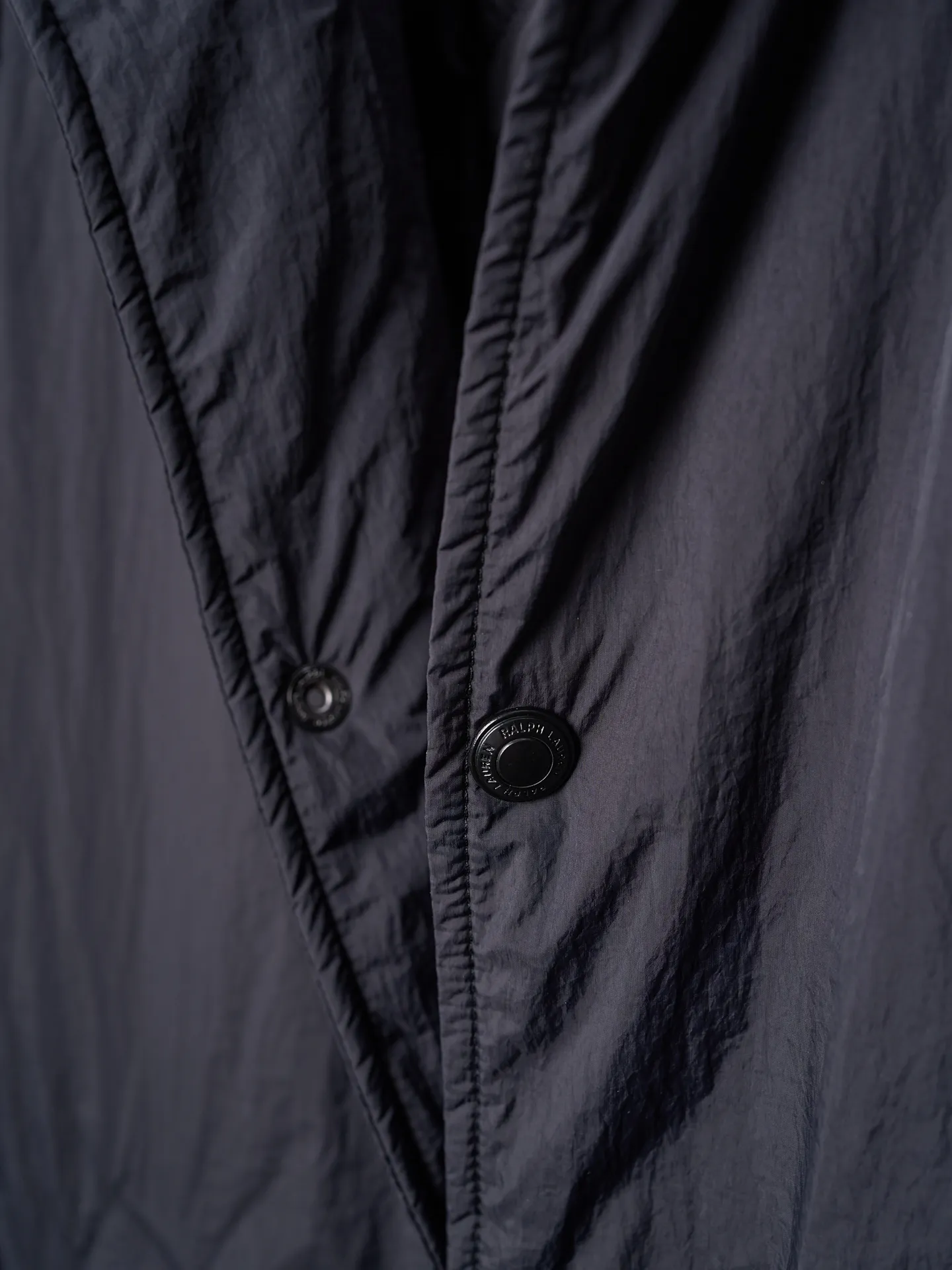 P640 Actual auction] Ralph Lauren/Ralph Lauren Pony Red Label lightweight cotton lapel coach jacket [Ready stock] S M L XL Material: high-density nylon taffeta Features: Density is about 210T-300T, smooth and slightly matte surface, excellent windproof and waterproof performance (with DWR water-repellent treatment), strong wrinkle resistance and easy care, in line with the positioning of American casual "durable and practical".  Color: Classic dark black, using vat dyeing process (dye penetrates into the fiber), the color fastness reaches ISO level 4 or above to avoid fading or color transfer after washing.  2. Lining fabric Material: Lightweight cotton-polyester blended lining (65% Polyester + 35% Cotton) Function: Reduce friction between the fabric and inner clothing, improve wearing smoothness; blended material has both breathability and durability to avoid the stuffy feeling of pure nylon lining.  Version and cutting process Version: Classic Coach Jacket, loose version, slightly dropped shoulder line (shoulder width is 1-2cm wider than the standard version), length to the hips, and slightly tapered straight sleeves, taking into account both freedom of movement and casual style. Embroidery technology: Polo horse logo on the left chest: flat satin stitch embroidery (satin embroidery), embroidery thread: 100% polyester high color fastness embroidery thread (the color number is consistent with the brand’s standard red color card), stitch density 12-15 stitches/cm, the outline of the horse logo is clear, and the details of the rider and horse are burr-free.  Embroidery positioning: precise positioning through the template (12cm from the neckline and 8cm from the placket) to ensure left and right symmetry and centering.  Topstitching technology: The seams of the body are made of double-needle flat seams (needle pitch 3cm/10 needles), the stitches are smooth and straight, the stitching color is dark black (the same color as the fabric), and the stitch width is 0.5cm, which enhances firmness while forming simple decorative lines.  1. Main body splicing, splicing of the front placket and body: The placket is made of double-layer folding + flat seam splicing, with a thickness of about 0.3cm to ensure that the buttons are not easily deformed when fixed; the edges of the placket are cut with a hot knife to avoid burrs.  Sleeve panels are spliced ​​to the body: the armholes are spliced ​​with round-head keyhole machine seams + flat seams. After splicing, the armholes have a natural curvature and no sense of tightness during movement; the height of the sleeves is about 8-10cm, which is in line with the loose characteristics of casual jackets.  Main button: black urea resin button, matte surface treatment, buttonholes are hand-made keyholes (6 strands of cotton thread, keyhole density 8 stitches/mm), the edges of the eyelets are smooth and without burrs.  Collar buttons: The first button on the collar is a hidden button (diameter 12mm), which prevents the collar from opening and improves the neatness of wearing.